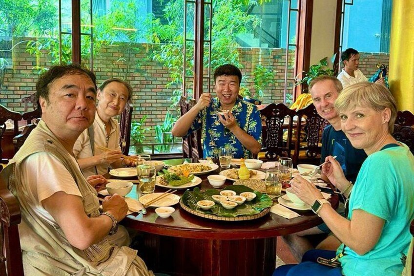 Un grupo de personas cenando en una mesa con distintos platos y bebidas. 5