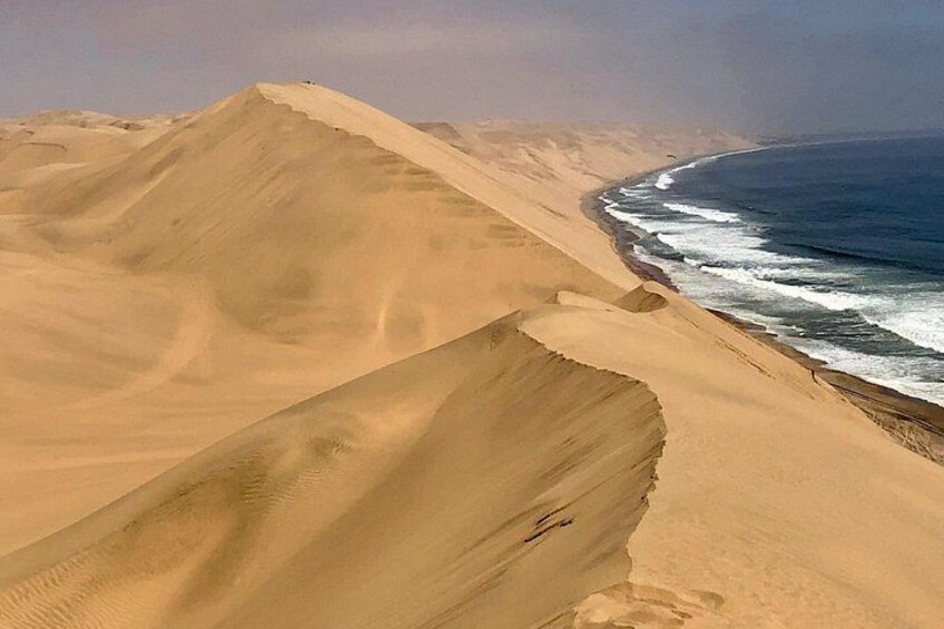 Sand dunes, ocean waves, and a clear sky. 5