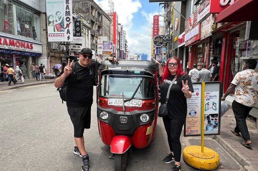 En röd, automatisk rickshaw stod parkerad på en livlig gata, omgiven av folk. 2
