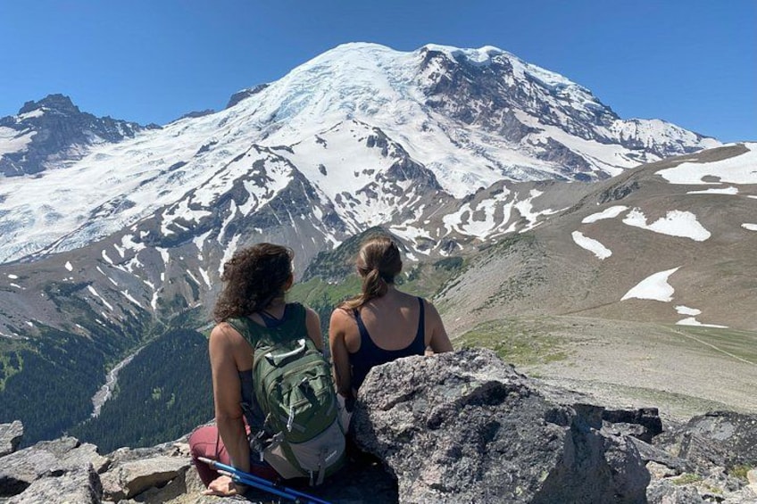 Two hikers on a mountain trail with a snow-capped peak in the background. 4