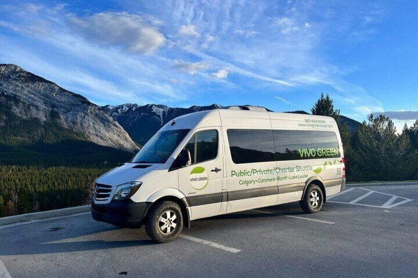 A white van with 'Vivo Green' branding parked in a lot with mountains in the background. 4