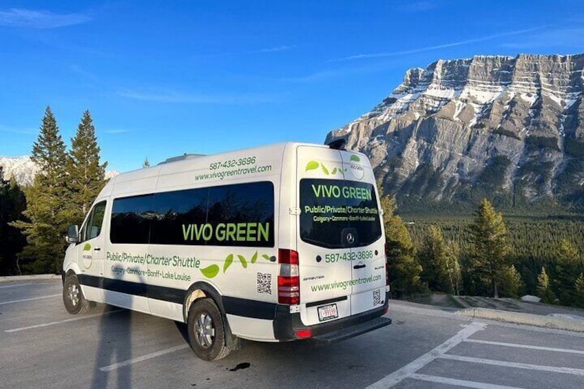 A white van with 'Vivo Green' branding parked on a road with a mountainous backdrop. 1