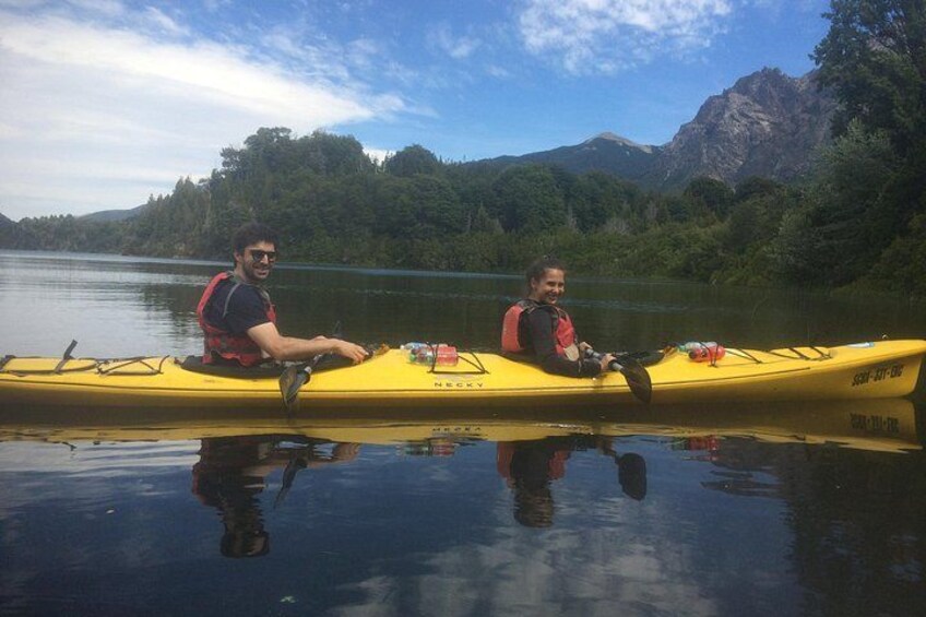 Two people kayaking on a calm lake with mountains in the background. 2