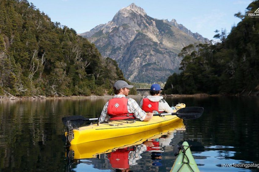 Two people kayaking on a calm lake with mountains in the background. 3