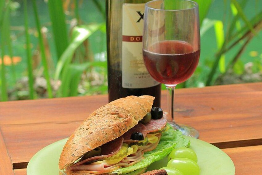 A sandwich on a green plate with a glass of red wine and a bottle in the background. 4