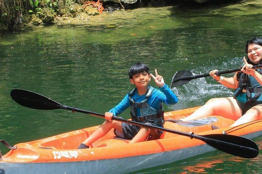 Two people kayaking on a calm river surrounded by greenery. 3