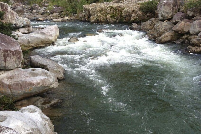 A river with white water rapids, surrounded by large rocks and boulders. 2