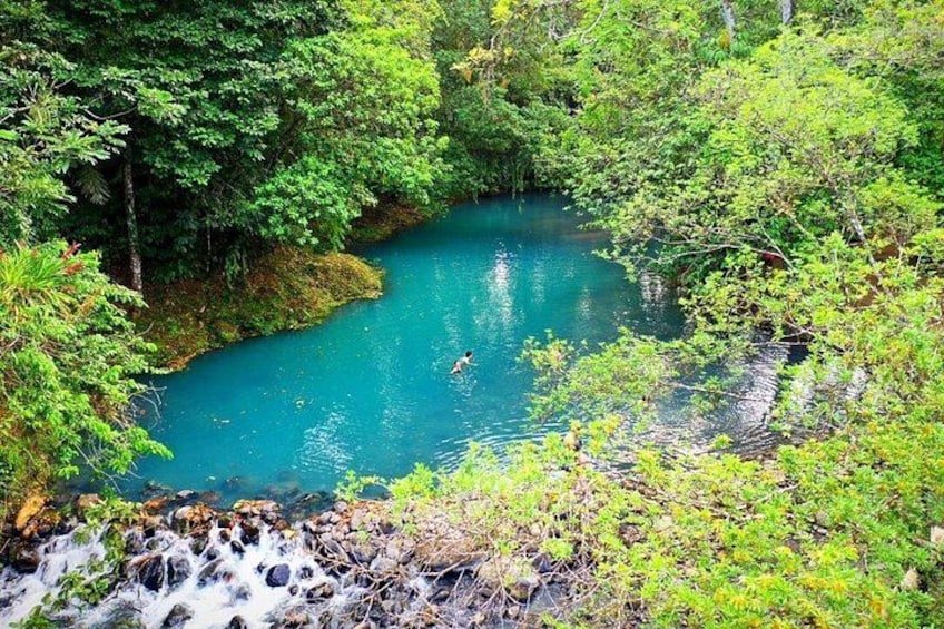 Un río turquesa rodeado de follaje verde denso, con una cascada al frente. 3