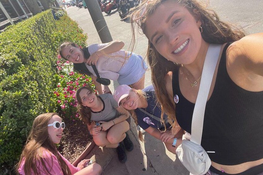 Un grupo de personas tomándose un selfie en un entorno al aire libre, con follaje y un sendero pavimentado. 5