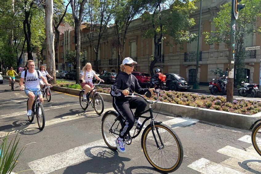 Cyklister på en stadsgata med byggnader och träd i bakgrunden. 5