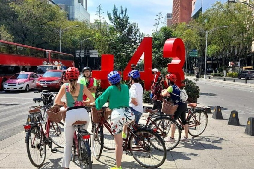 Un groupe de cyclistes sur un trottoir de la ville, avec un grand panneau rouge portant le chiffre « 43 » en arrière-plan. 5