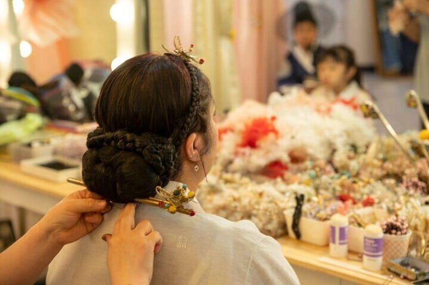 A person getting their hair styled with a bun adorned with decorative hairpins. 1