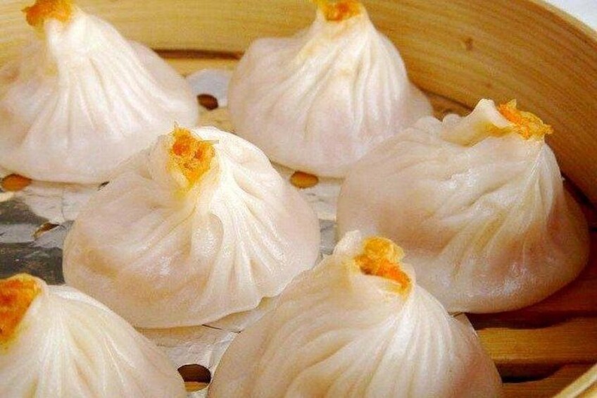 A bamboo steamer with several white dumplings. 4