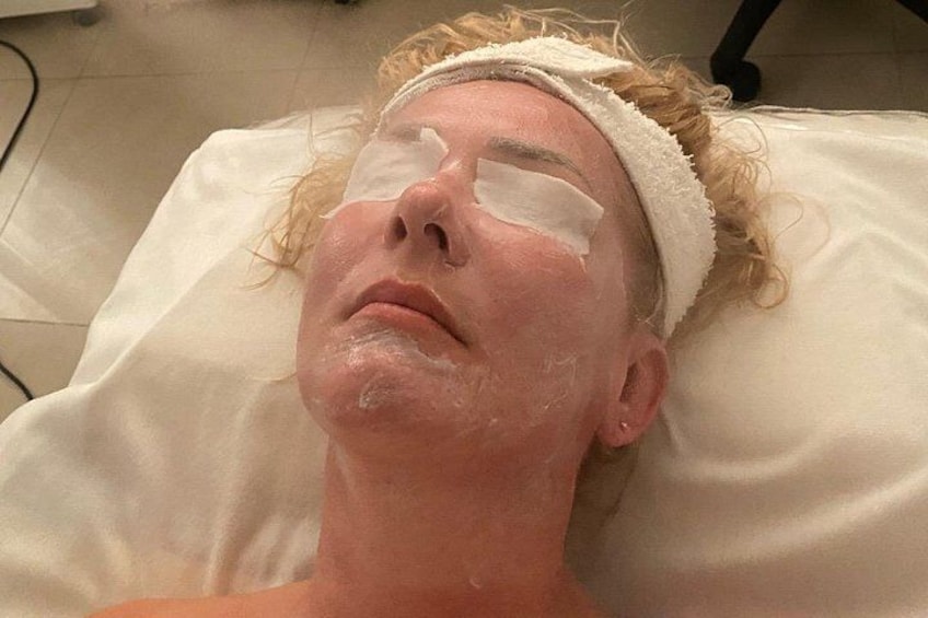 A person lying on a bed with a white pillow, wearing a white headband, and a white sheet. 1