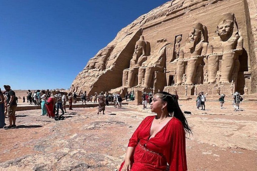 A large ancient Egyptian temple with massive statues and tourists. 1
