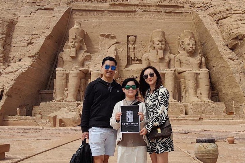 A group of people standing in front of a large ancient Egyptian monument with hieroglyphics and statues. 3
