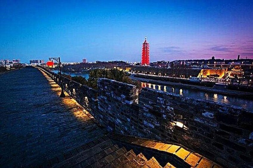A river with a bridge, a red tower, and a stone wall. 4