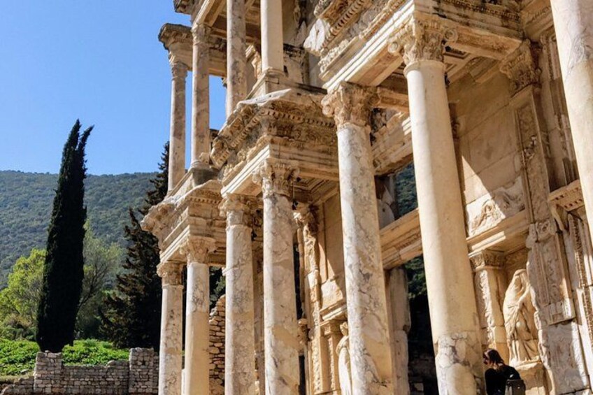 Ancient ruins with columns and statues, set against a mountainous backdrop. 4