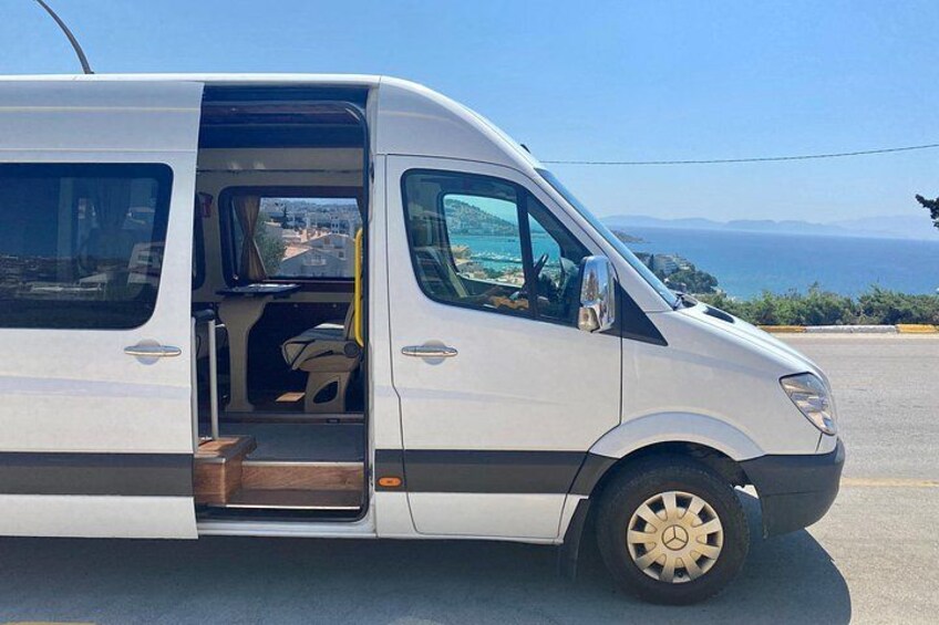 En hvid varevogn holder parkeret på en vej med en smuk udsigt over havet og bakker i baggrunden. 1