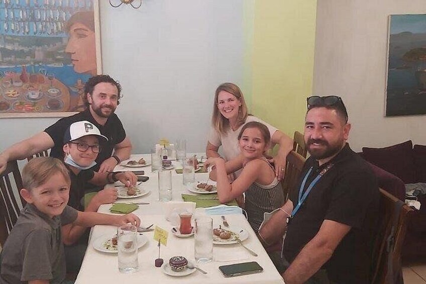Una famiglia a tavola, con piatti di cibo, bicchieri e uno smartphone. 5