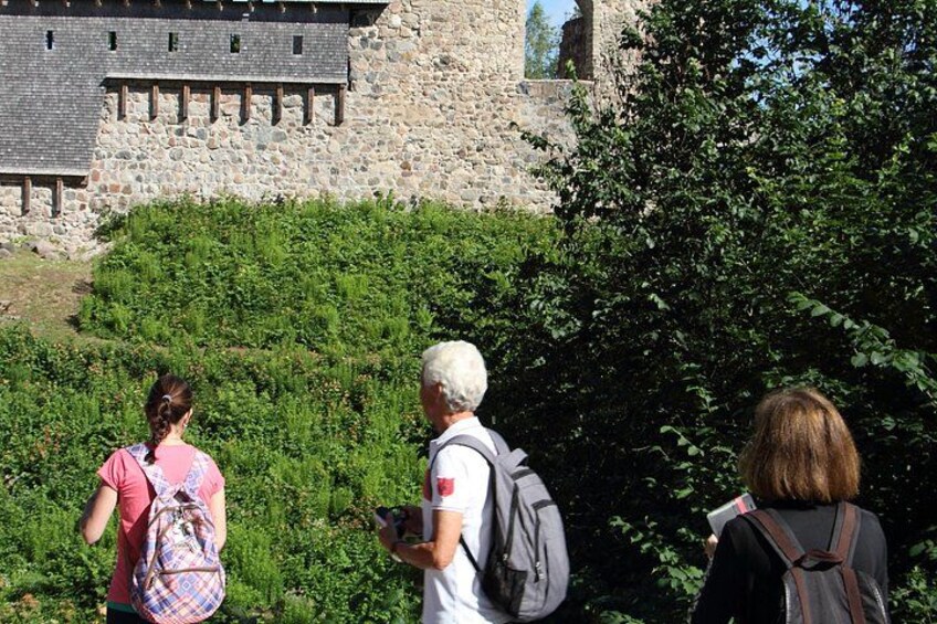 Un grupo de personas caminando cerca de un edificio de piedra con un ventanal grande. 1