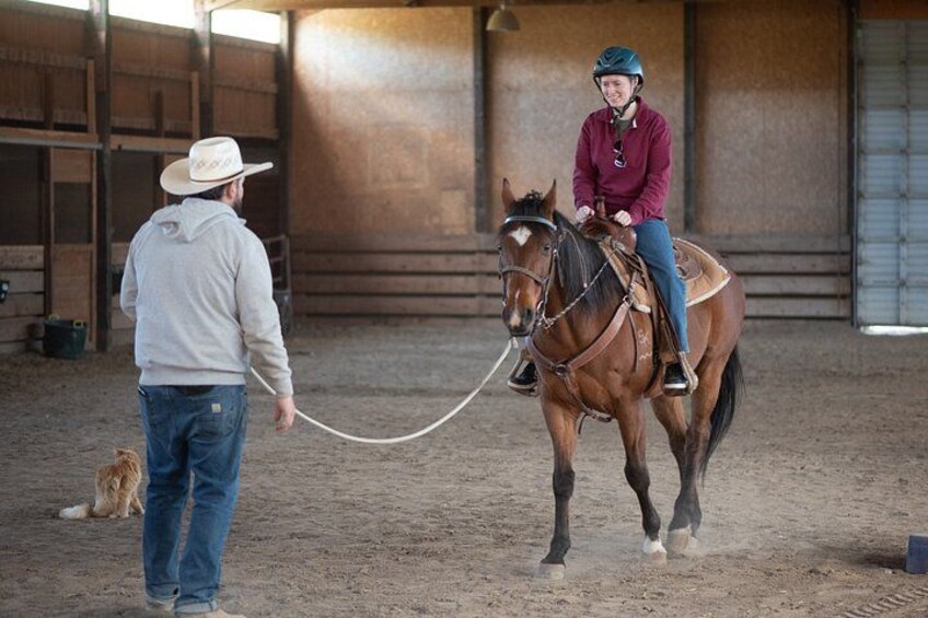 A person riding a horse in an indoor arena, with another person holding a lead rope. 5