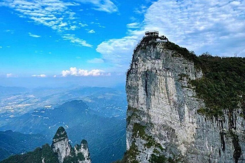 A mountain peak with a structure on top, a valley below, and a clear sky. 5
