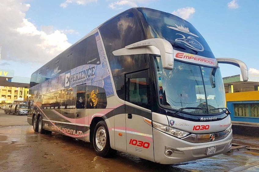 En stor bus med 'Experience' og 'Emperor' på, parkeret på en våd overflade. 4