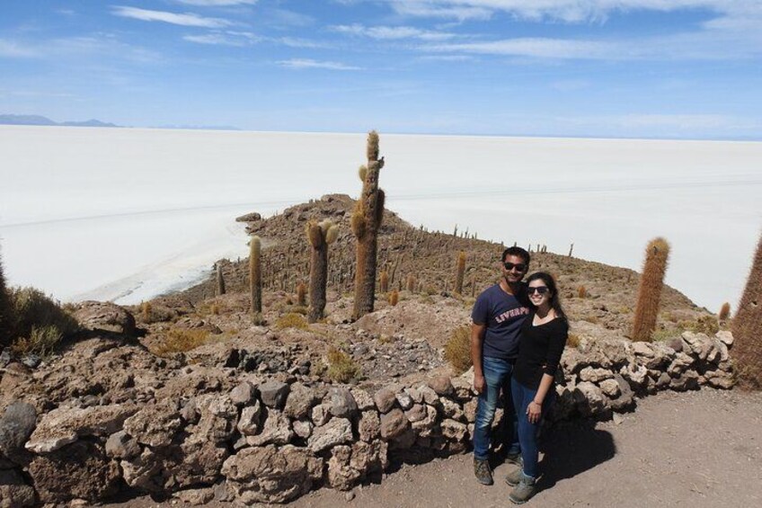 A couple standing near a rocky outcrop with cacti, overlooking a vast salt flat. 2
