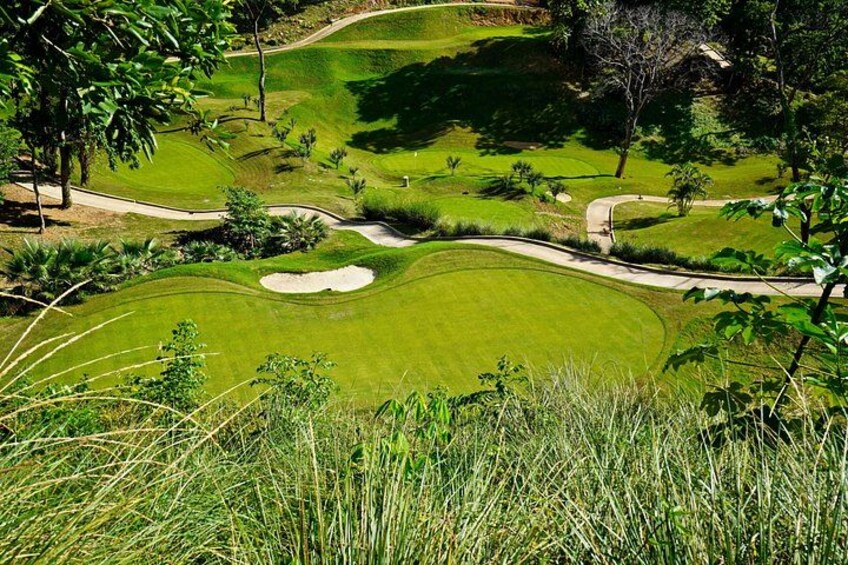 Een golfbaan met zandbunkers, bomen en een verzorgd gazon. 1