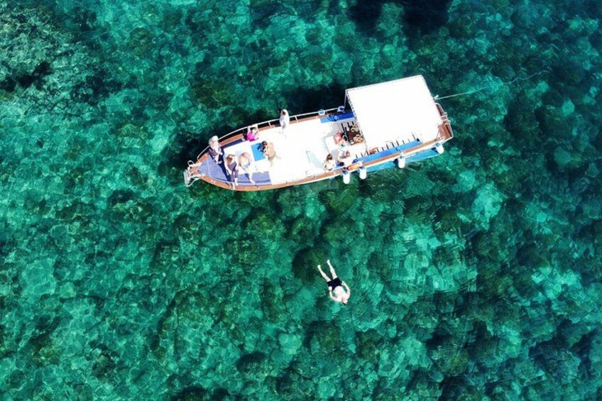 Un bateau avec des personnes à bord, naviguant sur une étendue d’eau d’un bleu limpide, entourée de coraux. 1