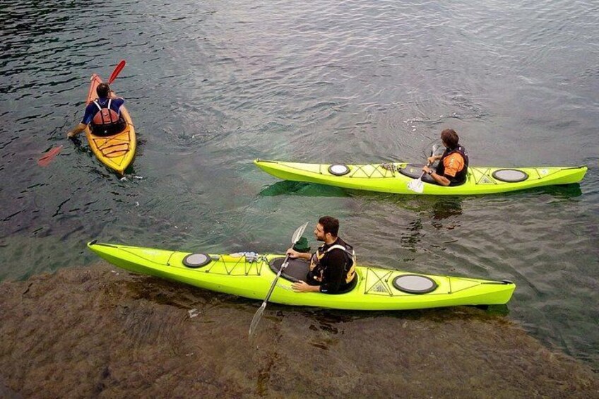 Three kayaks on calm water, one yellow and two green, with paddlers. 3