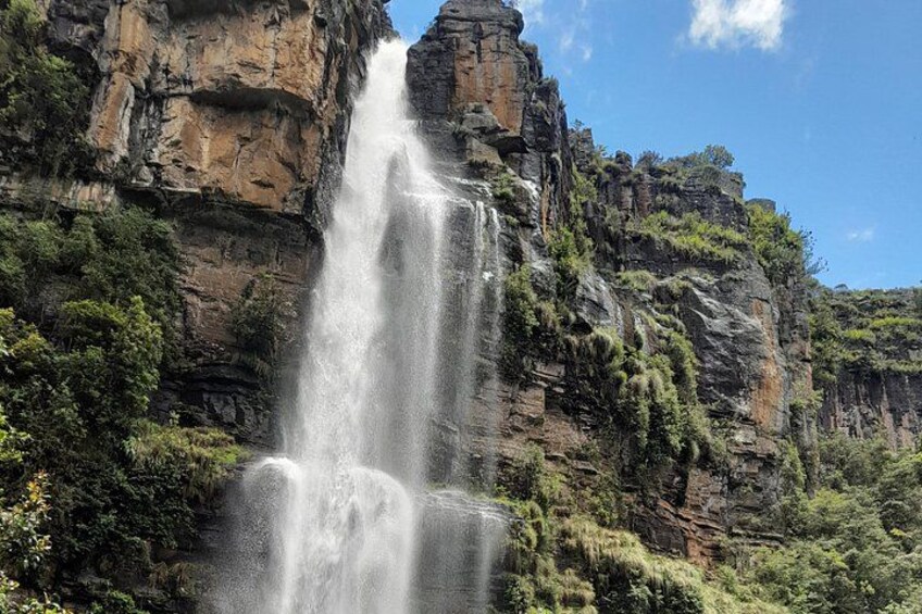 A waterfall cascading down a rocky cliff surrounded by greenery. 2