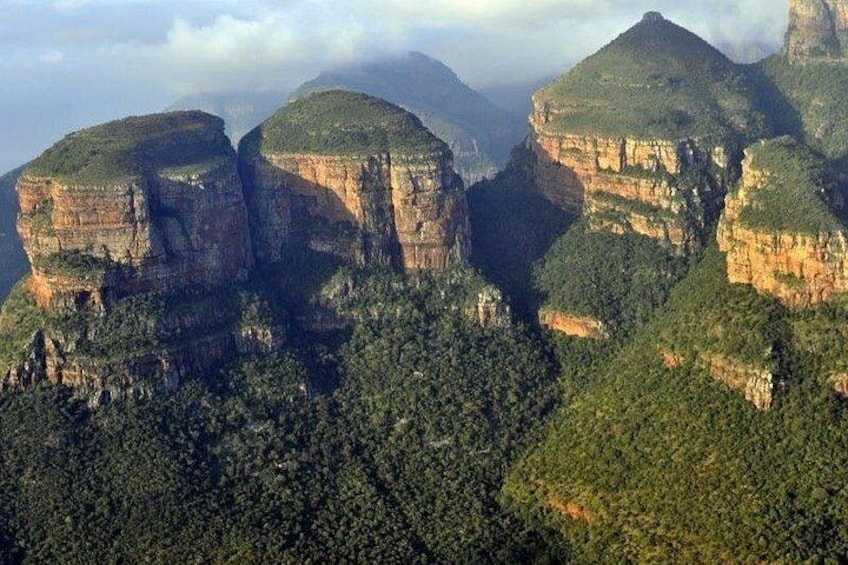 A mountainous landscape with prominent rock formations and dense forest. 3