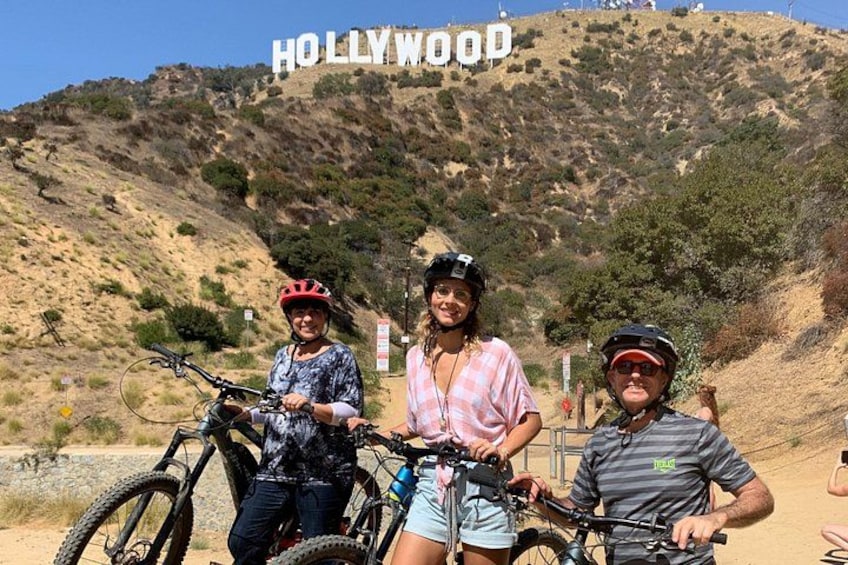 Tre persone con biciclette di fronte al cartello di Hollywood. 3