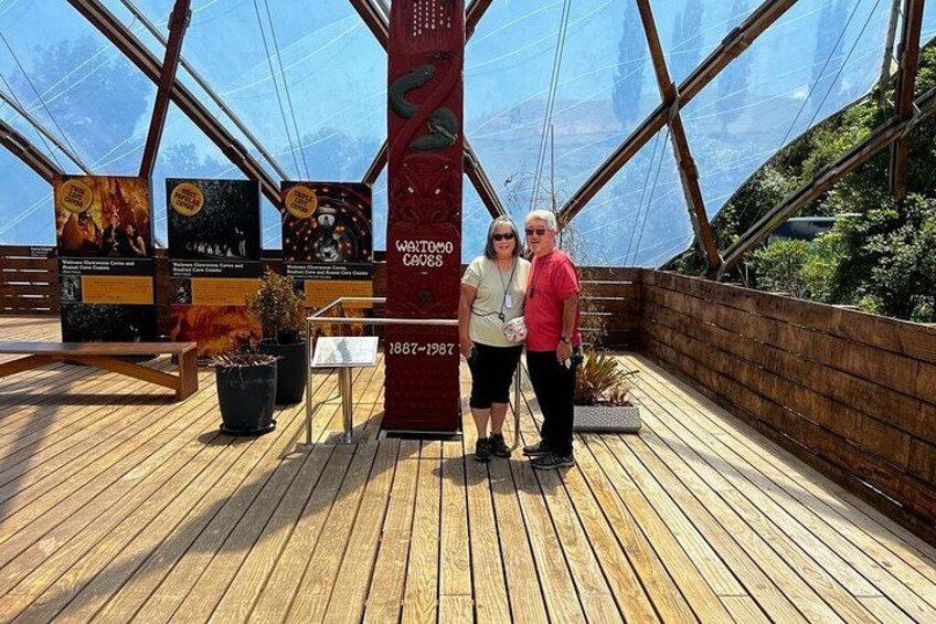 A wooden deck with a glass ceiling, a red pillar with text, and informational signs. 4