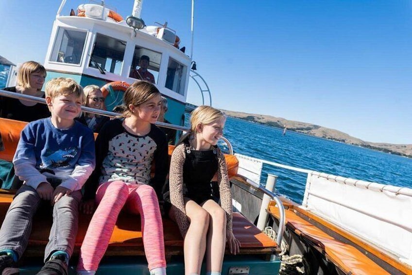 Eine Gruppe von Menschen auf einem Boot vor einem wolkenlosen, blauen Himmel und ruhiger See. 2
