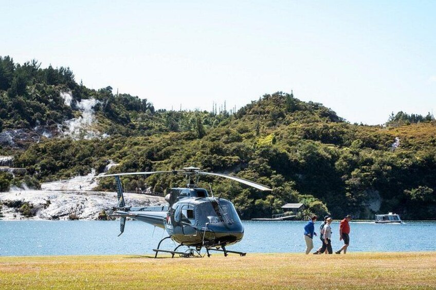 En helikopter på en græsplæne tæt på vandet med bakker i baggrunden. 1