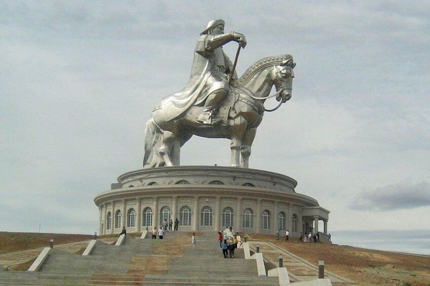 A large equestrian statue on a circular pedestal with steps leading up to it, surrounded by a few people. 4