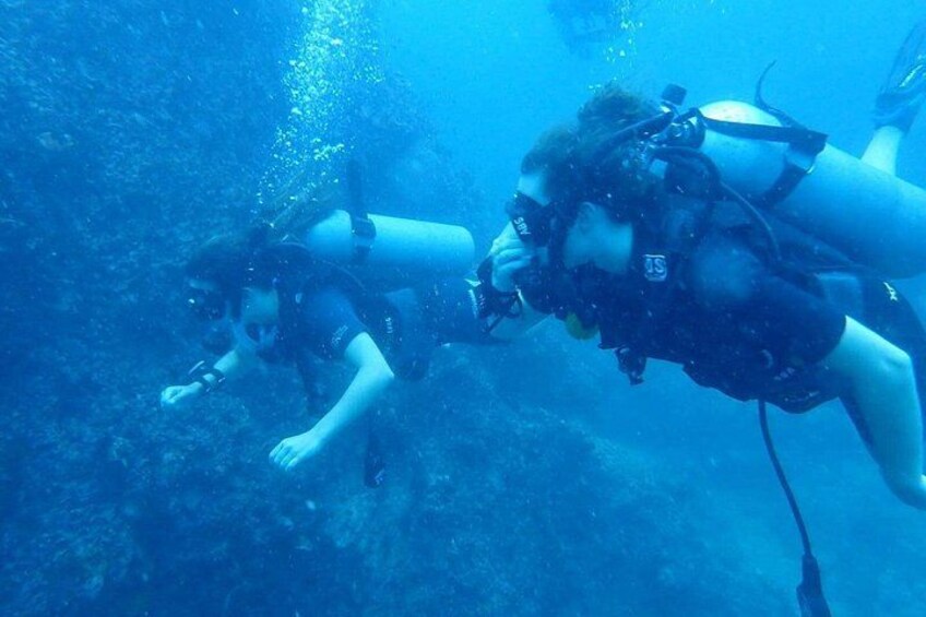 Two scuba divers underwater with fins and tanks. 2