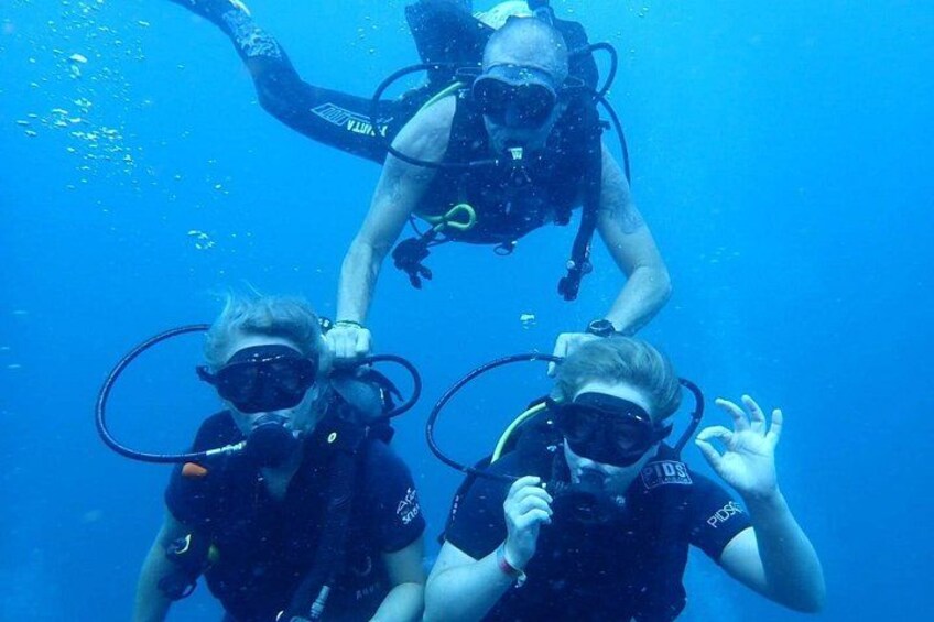 Three scuba divers underwater with fins and tanks. 1