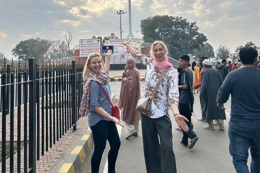 A group of people walking on a bridge with a fence on one side and a signboard in the background. 4