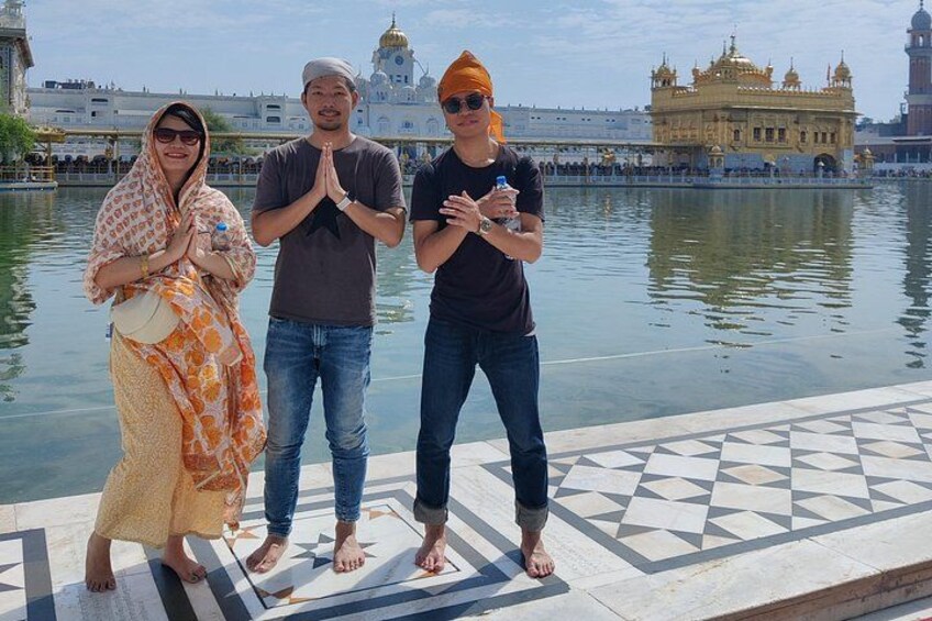 Three people standing by a body of water with a large golden building in the background. 5