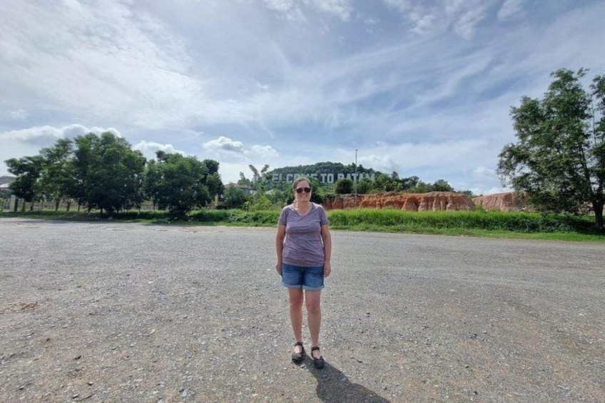 A person standing on a gravel road with trees and a sign in the background. 5
