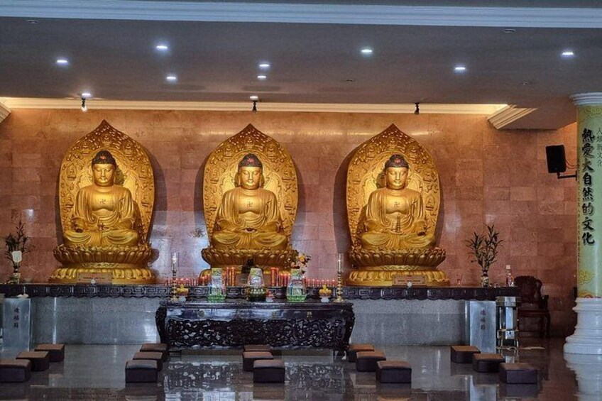 Three golden Buddha statues in a temple setting. 3
