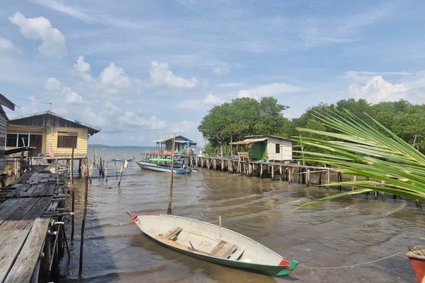 A wooden dock with a boat, floating houses, and a palm tree. 2