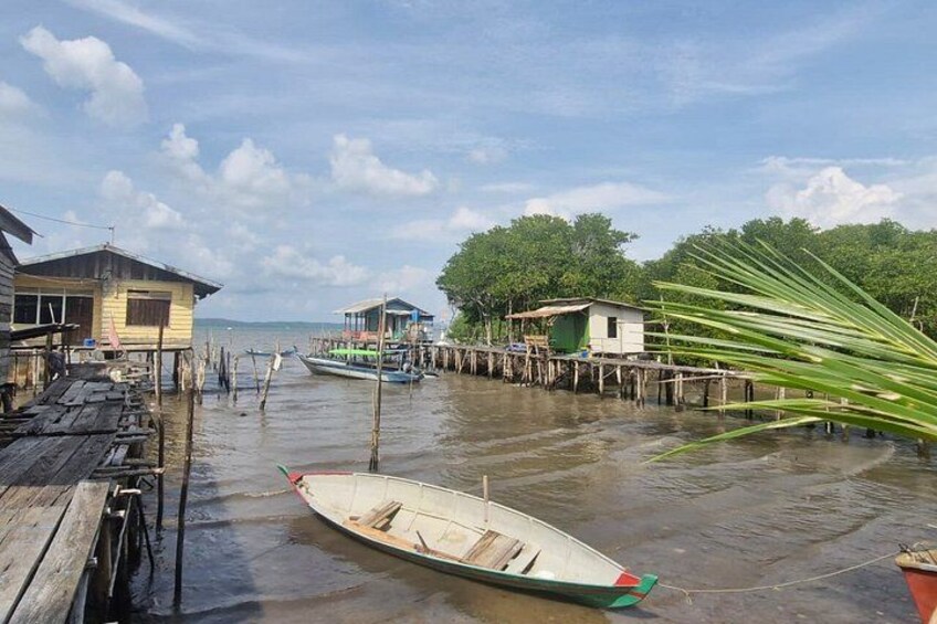 A wooden dock with a boat, floating houses, and a palm tree. 2
