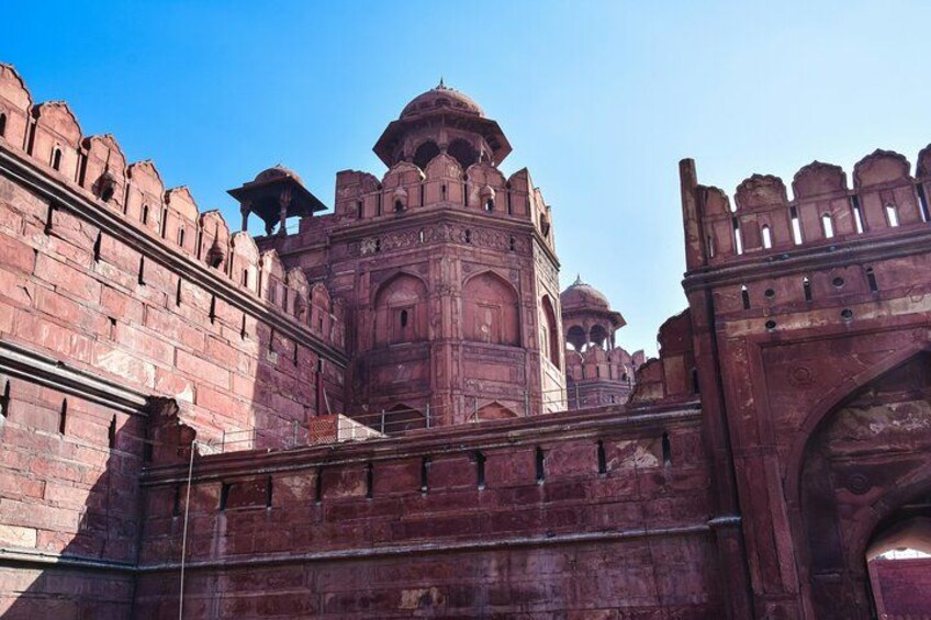 A historic fort with red sandstone walls, a large central tower, and a gate. 2