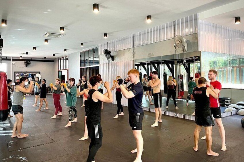 A group of people practicing martial arts in a gym with mirrors and punching bags. 5