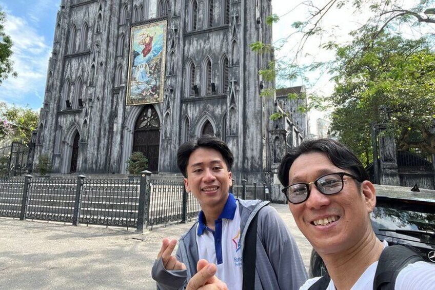 Two people in front of a Gothic-style church with a large mural. 5